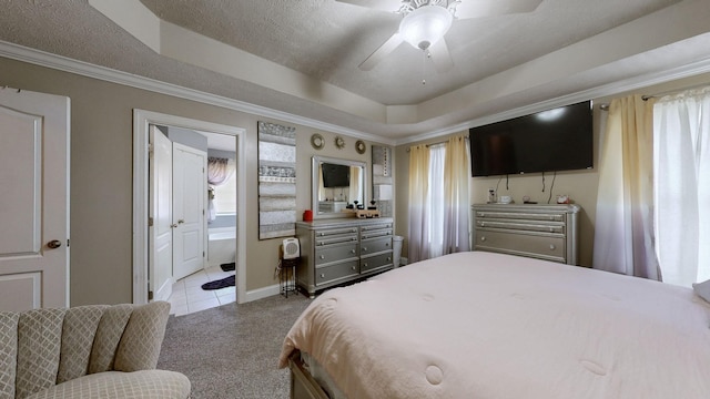 carpeted bedroom with ensuite bath, ceiling fan, ornamental molding, a textured ceiling, and a raised ceiling