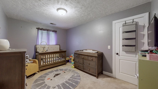 carpeted bedroom with a nursery area and a textured ceiling