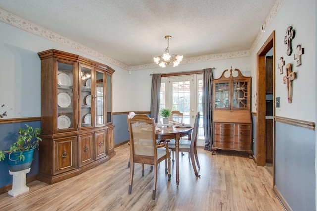 dining room featuring an inviting chandelier, light hardwood / wood-style flooring, and a textured ceiling