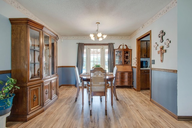 dining area featuring a chandelier, a textured ceiling, and light hardwood / wood-style floors