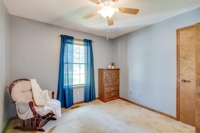 living area featuring ceiling fan, a textured ceiling, and carpet flooring