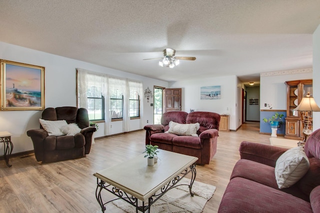 living room featuring ceiling fan, a textured ceiling, and light wood-type flooring