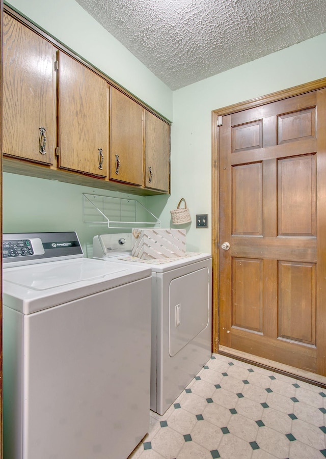 washroom with washer and clothes dryer, cabinets, and a textured ceiling