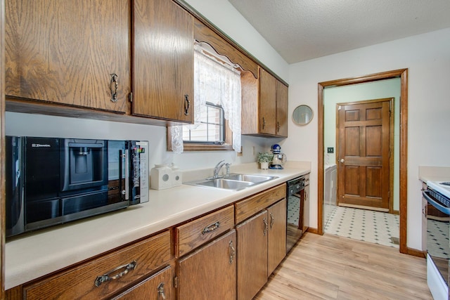 kitchen with light hardwood / wood-style floors, sink, a textured ceiling, and black appliances