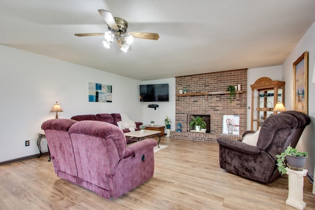 living room featuring a brick fireplace, light hardwood / wood-style flooring, and ceiling fan