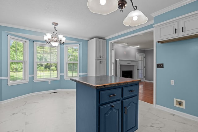 kitchen with white cabinetry, hanging light fixtures, ornamental molding, blue cabinetry, and light hardwood / wood-style floors