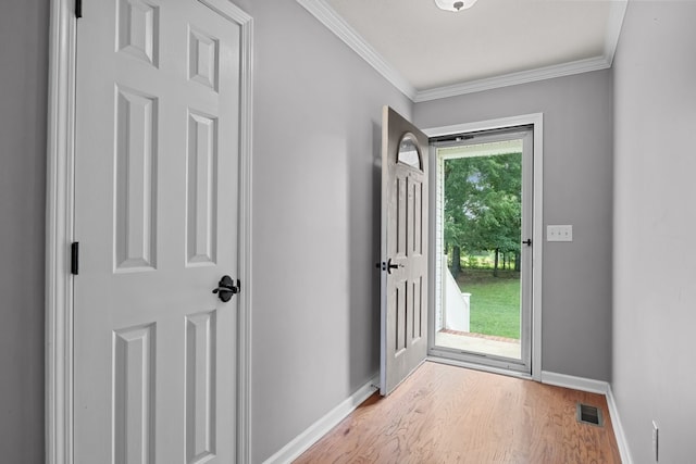 entryway with a healthy amount of sunlight, crown molding, and light wood-type flooring