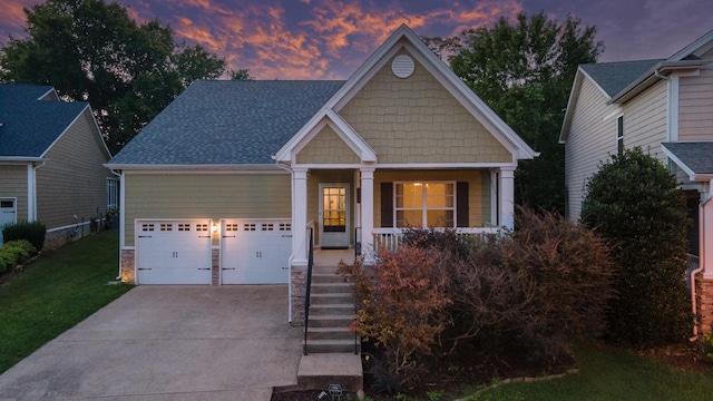 craftsman-style home with driveway, roof with shingles, an attached garage, a porch, and a front yard