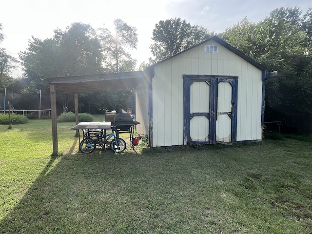 view of outbuilding with a trampoline, a yard, and a carport