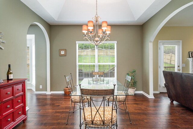 dining space with dark hardwood / wood-style floors, a notable chandelier, and a raised ceiling