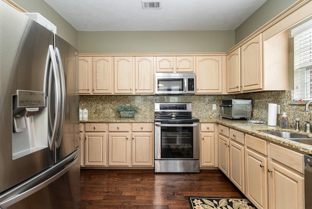 kitchen featuring dark wood-type flooring, light brown cabinetry, sink, stainless steel appliances, and light stone countertops