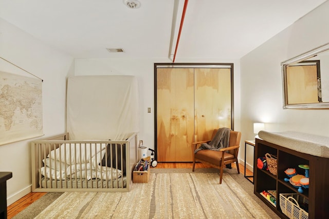 bedroom featuring hardwood / wood-style flooring, a crib, and a closet