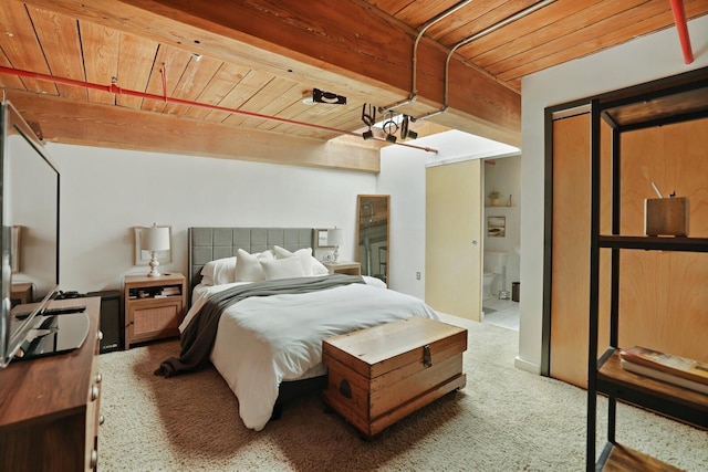 bedroom featuring beam ceiling, ensuite bath, wooden ceiling, and carpet flooring