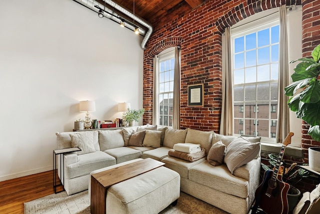 living room featuring track lighting, brick wall, and wood-type flooring