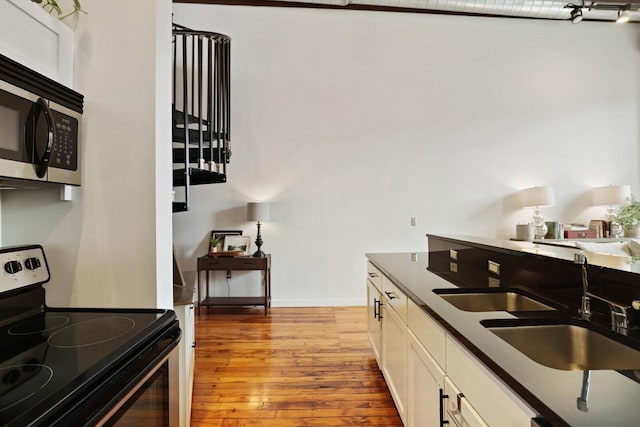 kitchen with white cabinetry, appliances with stainless steel finishes, sink, and light wood-type flooring