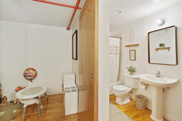 full bathroom with hardwood / wood-style flooring, toilet, sink, and shower / bath combo with shower curtain