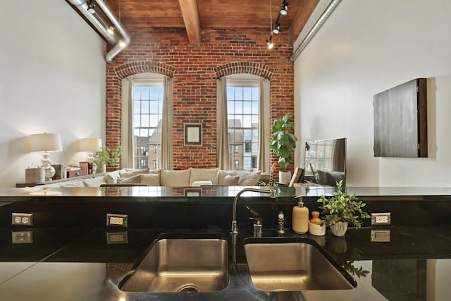 kitchen with brick wall, sink, wooden ceiling, and beam ceiling