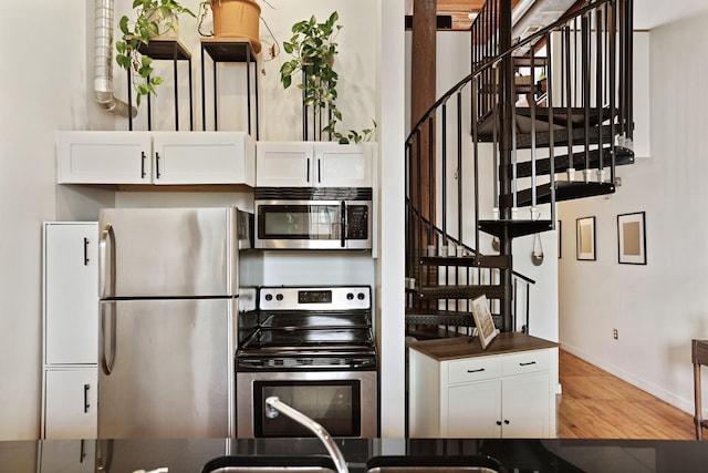 kitchen featuring white cabinetry, appliances with stainless steel finishes, and wood-type flooring