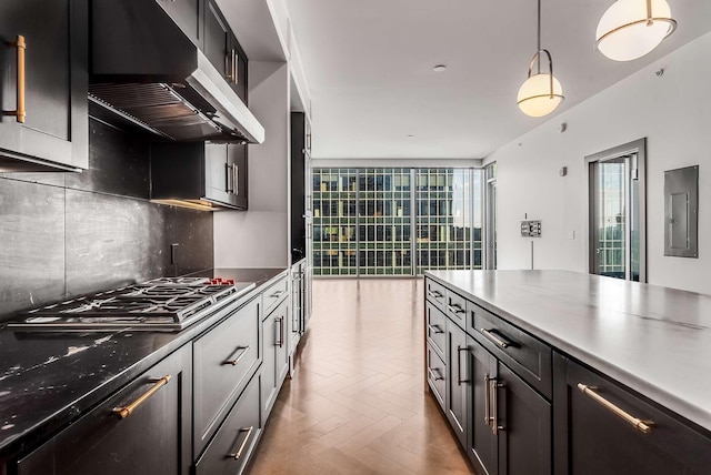 kitchen with tasteful backsplash, pendant lighting, electric panel, range hood, and stainless steel gas stovetop