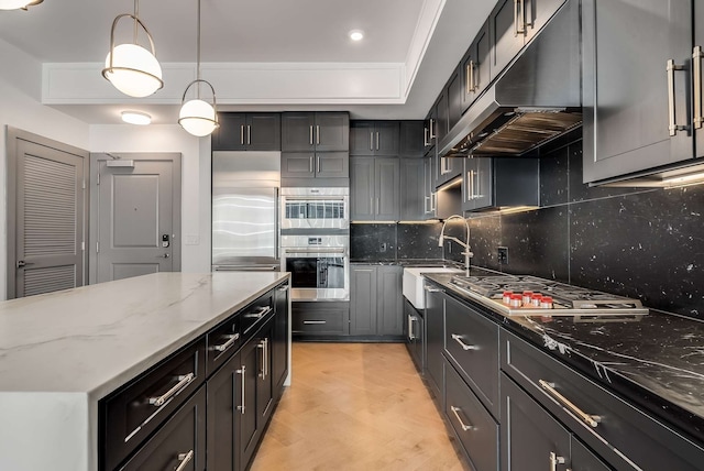 kitchen with stainless steel appliances, hanging light fixtures, sink, light stone counters, and backsplash