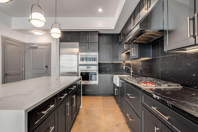 kitchen featuring light stone countertops, a sink, appliances with stainless steel finishes, under cabinet range hood, and light wood-type flooring