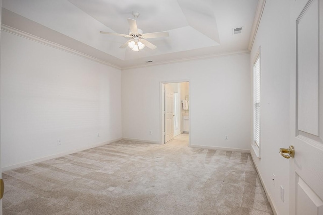 empty room featuring ceiling fan, light colored carpet, ornamental molding, and a raised ceiling