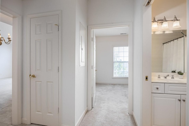 hall with sink and light colored carpet