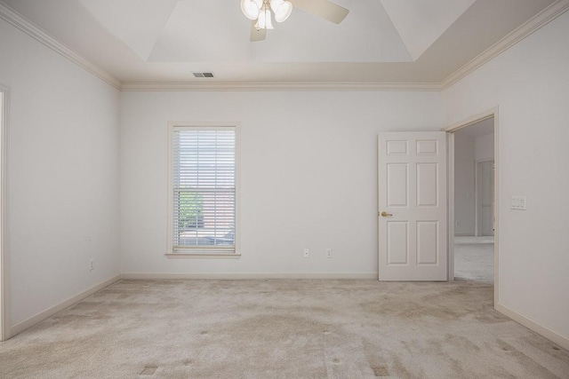 empty room with a raised ceiling, crown molding, and light colored carpet