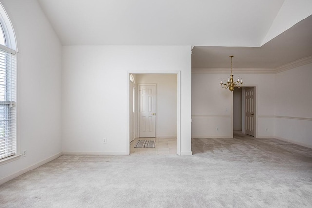 spare room featuring light carpet, crown molding, a wealth of natural light, and a chandelier