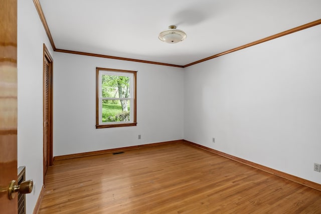 spare room featuring crown molding and light hardwood / wood-style floors