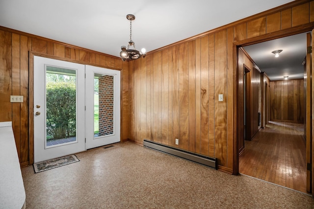 entryway featuring a chandelier, ornamental molding, a baseboard radiator, and wooden walls