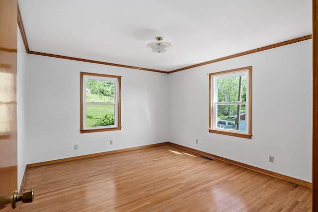 empty room with ornamental molding and light hardwood / wood-style floors