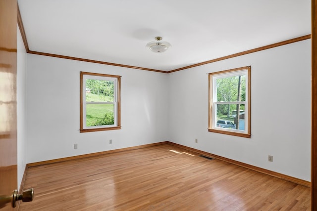 unfurnished room featuring baseboards, light wood finished floors, visible vents, and crown molding