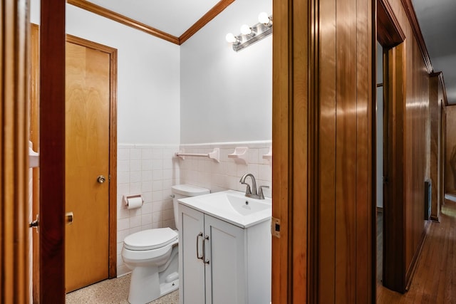 bathroom with crown molding, tile walls, toilet, wainscoting, and vanity