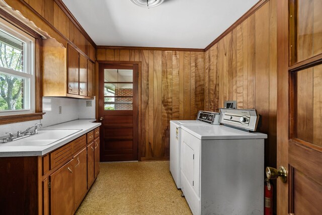 washroom with wooden walls, light colored carpet, washing machine and dryer, cabinets, and sink