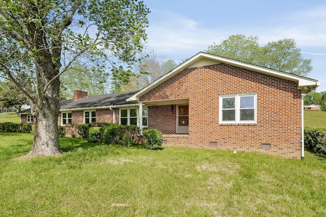 rear view of house with crawl space, a yard, a chimney, and brick siding