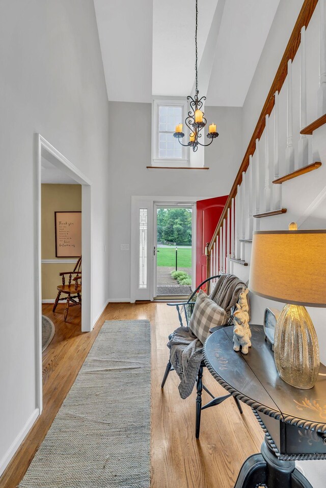 entryway with light hardwood / wood-style flooring, high vaulted ceiling, and an inviting chandelier