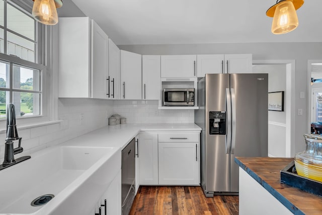 kitchen featuring dark hardwood / wood-style flooring, decorative light fixtures, appliances with stainless steel finishes, and tasteful backsplash