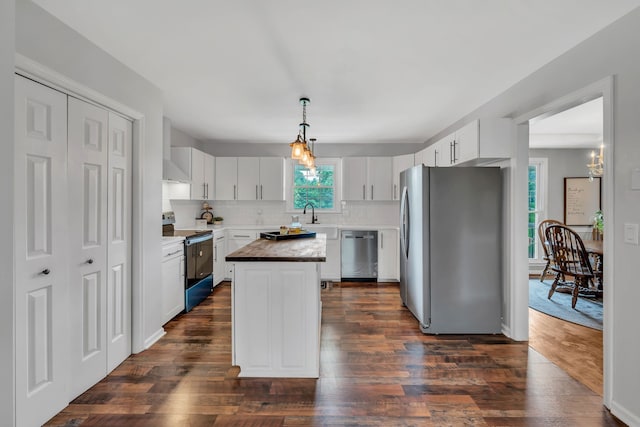 kitchen featuring butcher block countertops, dark wood-type flooring, a kitchen island, stainless steel appliances, and white cabinets