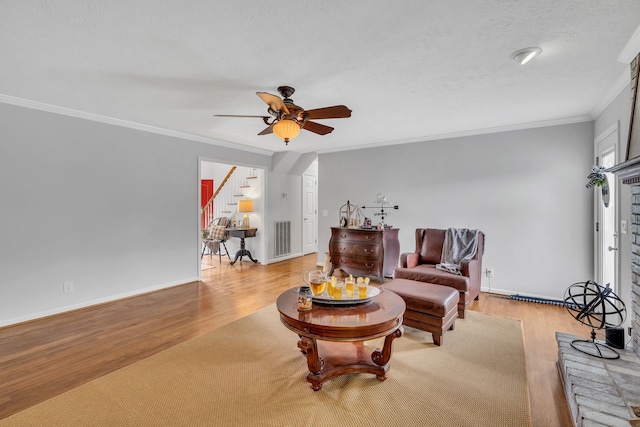 living room featuring light wood-type flooring, crown molding, and ceiling fan