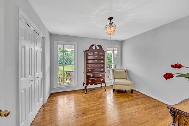 living area featuring light hardwood / wood-style floors, a chandelier, and a healthy amount of sunlight