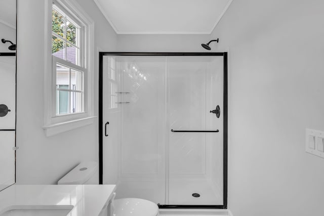 bathroom with crown molding, a shower with door, vanity, and toilet