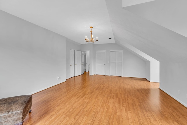 bonus room featuring light hardwood / wood-style flooring, vaulted ceiling, and an inviting chandelier