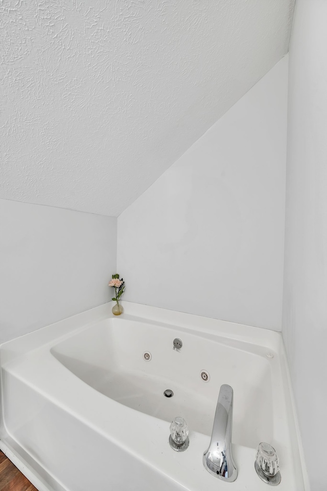 bathroom with a tub and a textured ceiling