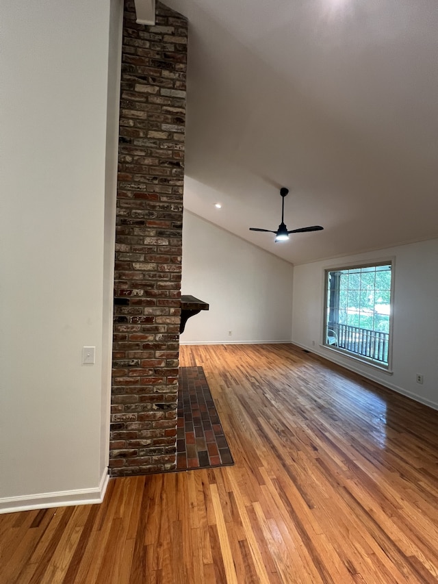 unfurnished living room featuring brick wall, ceiling fan, lofted ceiling, and hardwood / wood-style floors