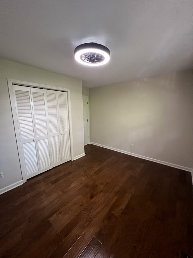 unfurnished bedroom with dark wood-type flooring and a closet