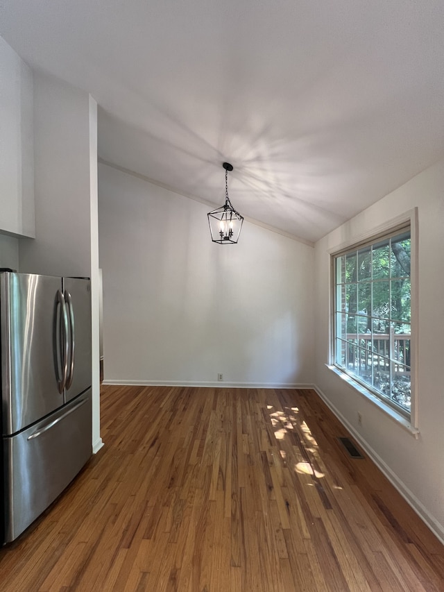 kitchen with hardwood / wood-style floors, pendant lighting, and stainless steel refrigerator