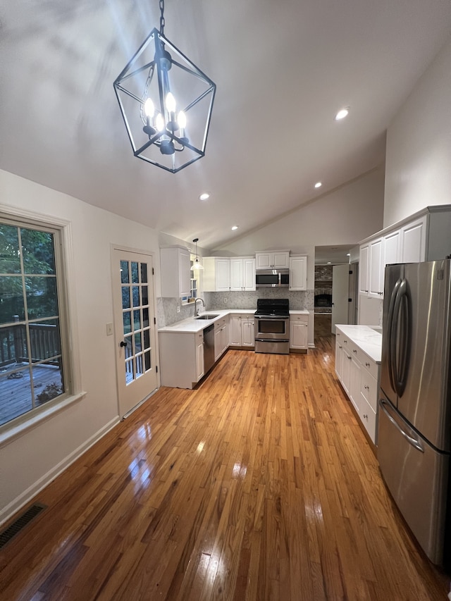 kitchen featuring stainless steel appliances, wood-type flooring, lofted ceiling, and tasteful backsplash