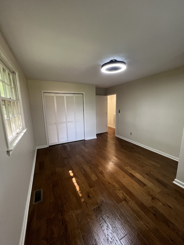 unfurnished bedroom featuring dark wood-type flooring and a closet