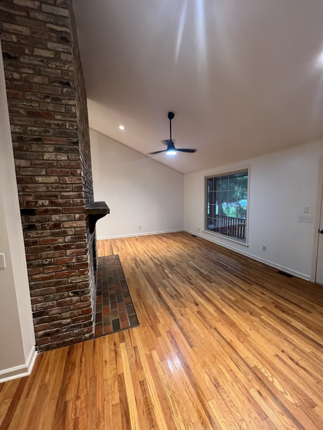 unfurnished living room featuring hardwood / wood-style flooring, brick wall, and ceiling fan